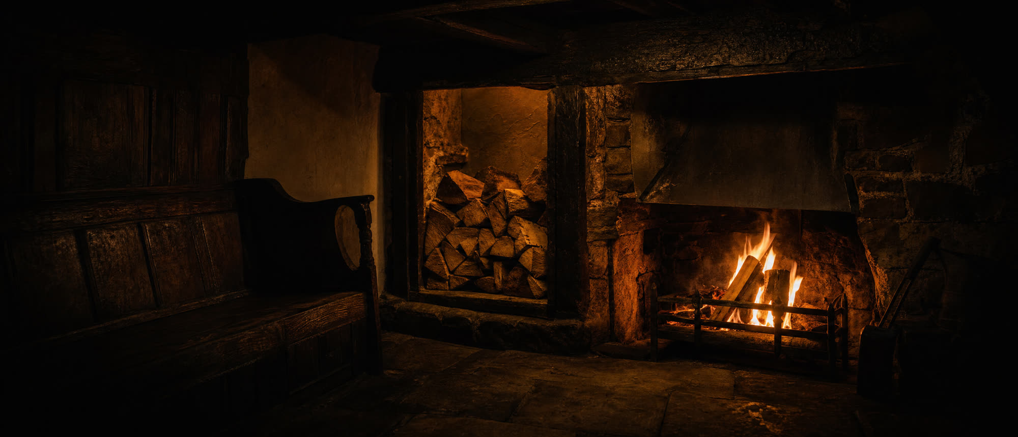 A wood fire burning in a pub's inglenook fireplace, with split logs stacked beside it